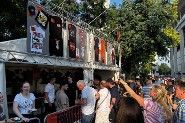 Side view of crowds eagerly awaiting to buy merchandise from the Bruce Springsteen stand.