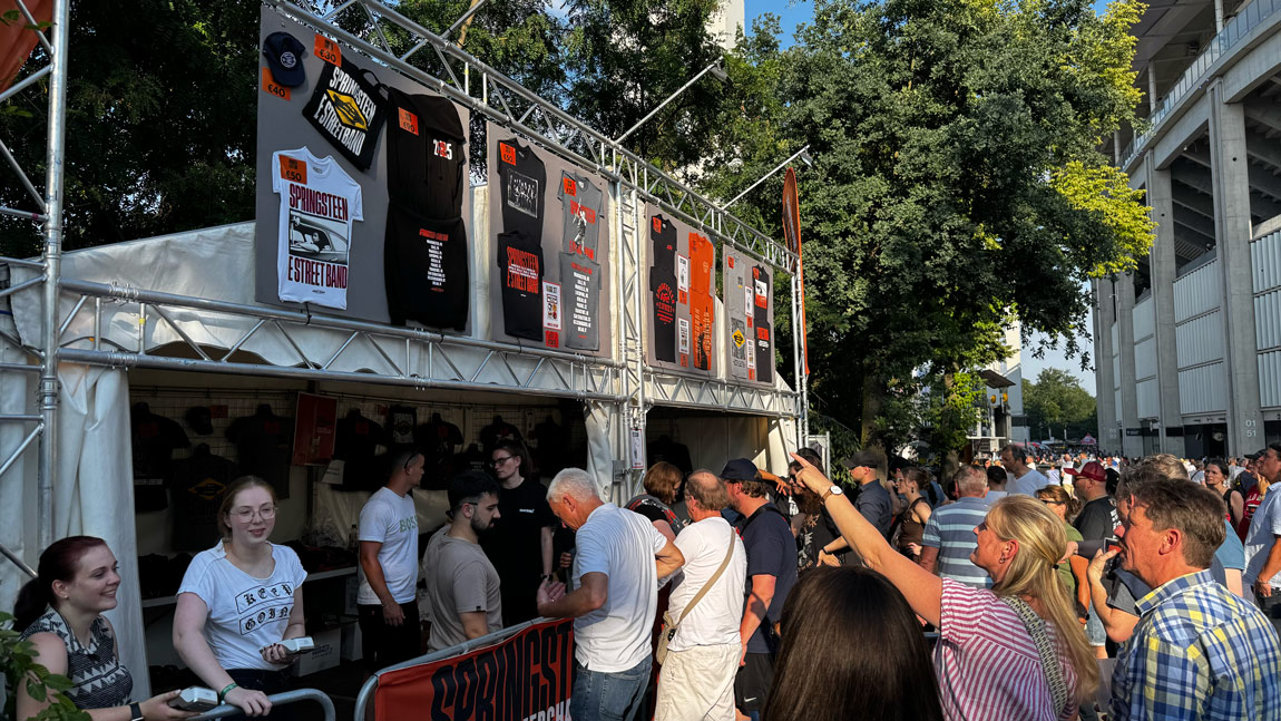 Side view of crowds eagerly awaiting to buy merchandise from the Bruce Springsteen stand.